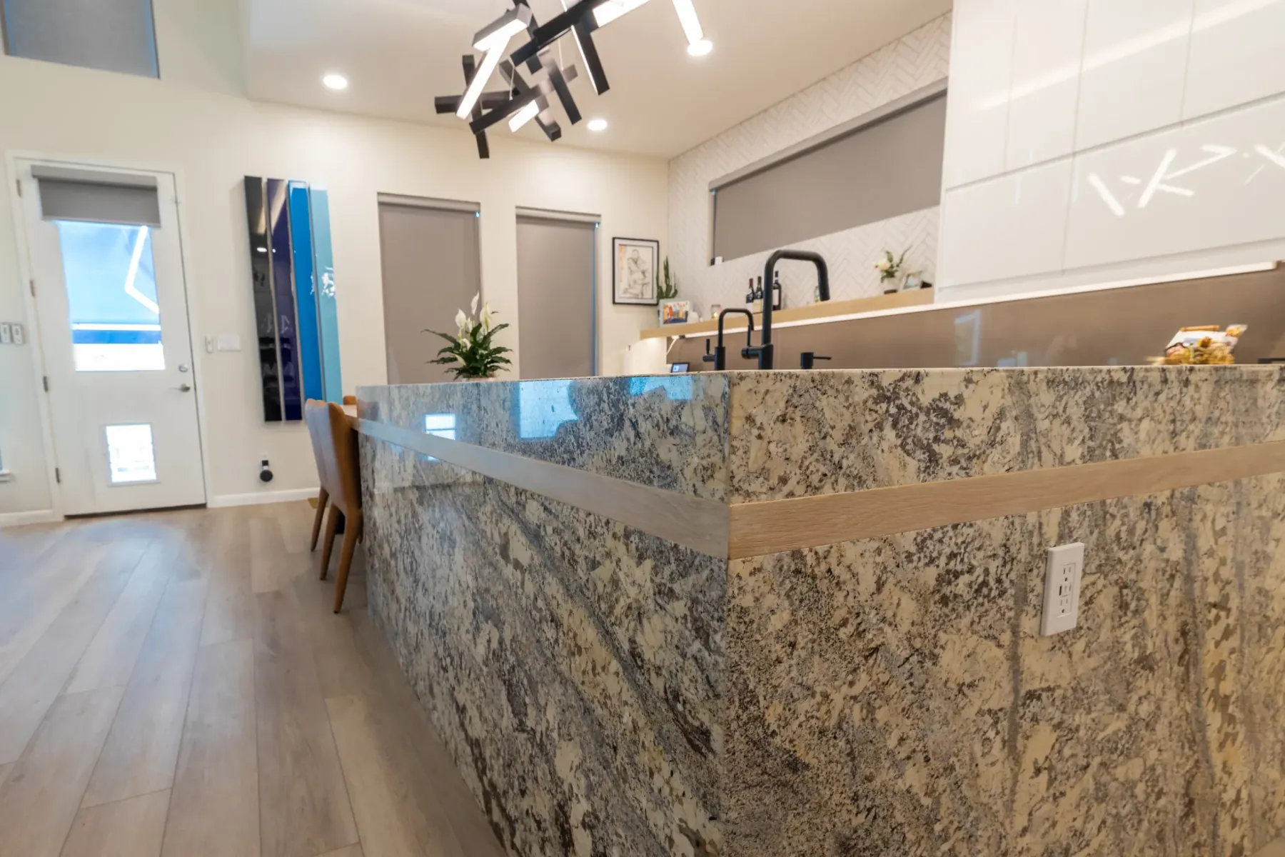 Wide view of a granite waterfall island with a light wood band and black faucet, Bee Cave, TX kitchen