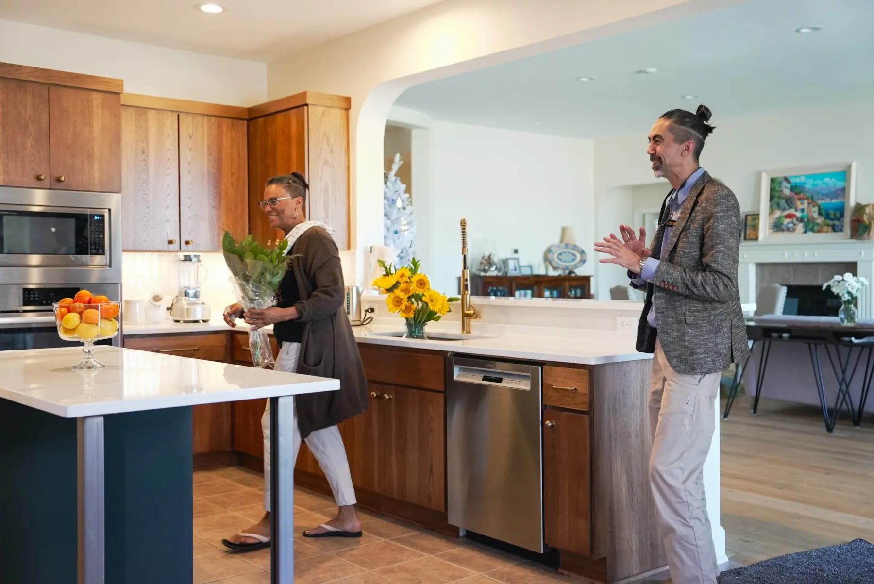 Two people greeting each other in a wood and white kitchen with a brass faucet, Austin remodel
