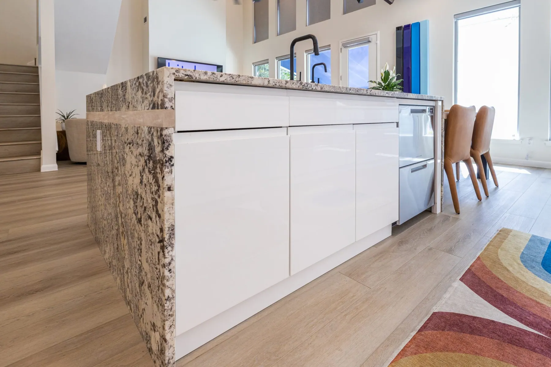 Granite waterfall island with glossy white handleless cabinets and light plank flooring, Bee Cave kitchen remodel