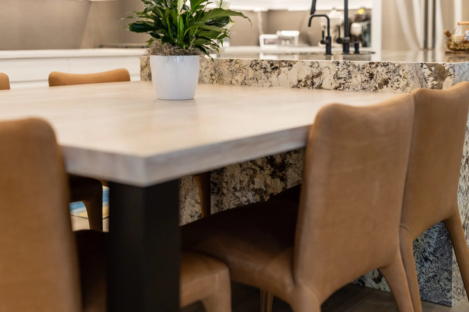 Light wood table extending from a granite island, with tan upholstered chairs, Bee Cave kitchen